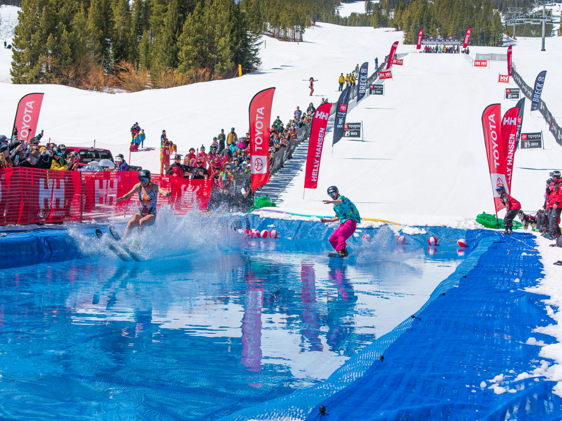 A skiier and a snowboarder float over water during the Breckenridge pond skim